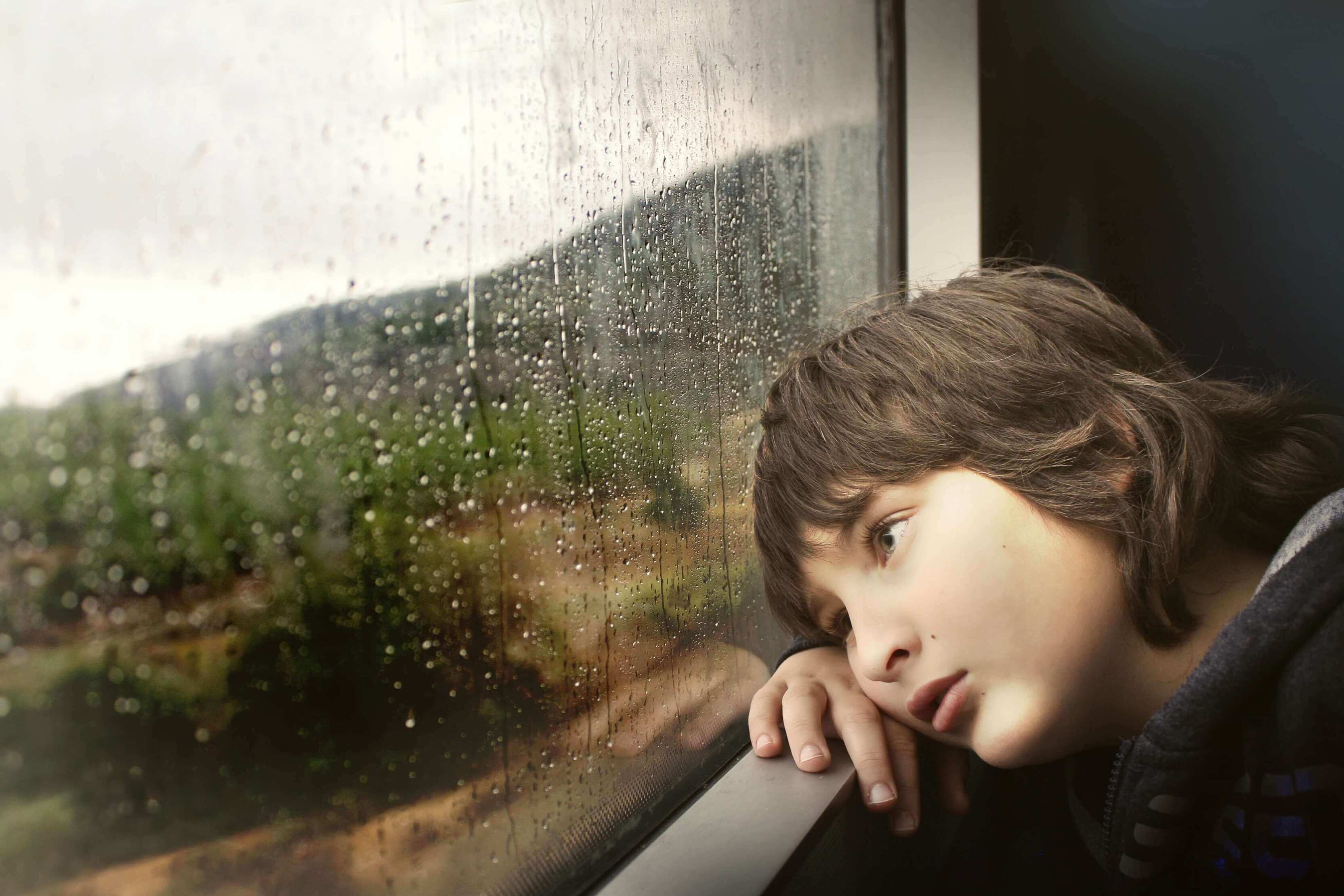 Trauriger Junge, der aus dem Fenster schaut