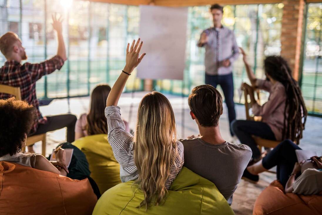 Seminargruppe mit Teilnehmer*innen, die sich melden