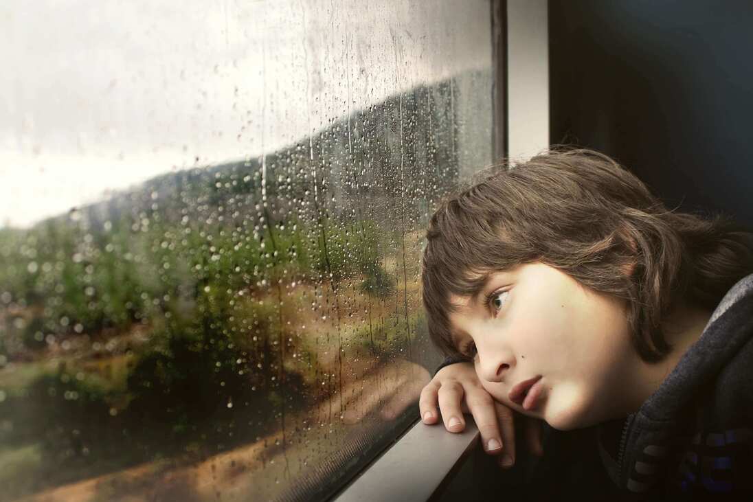 Trauriger Junge, der aus dem Fenster schaut