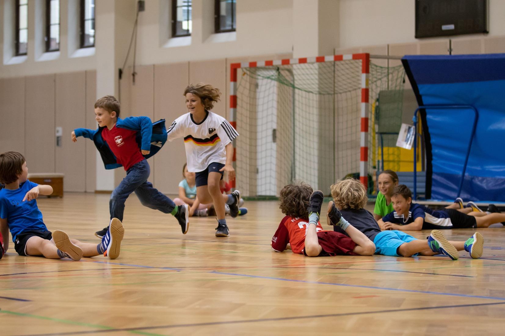 Kinder spielen Fangen in der Turnhalle