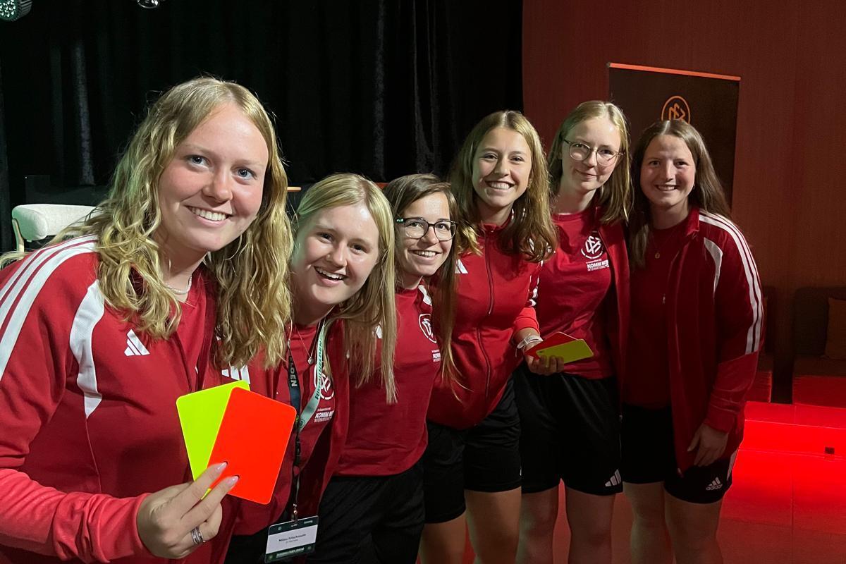 Sechs junge Frauen im Fußballoutfit mit Schiedsrichterkarten