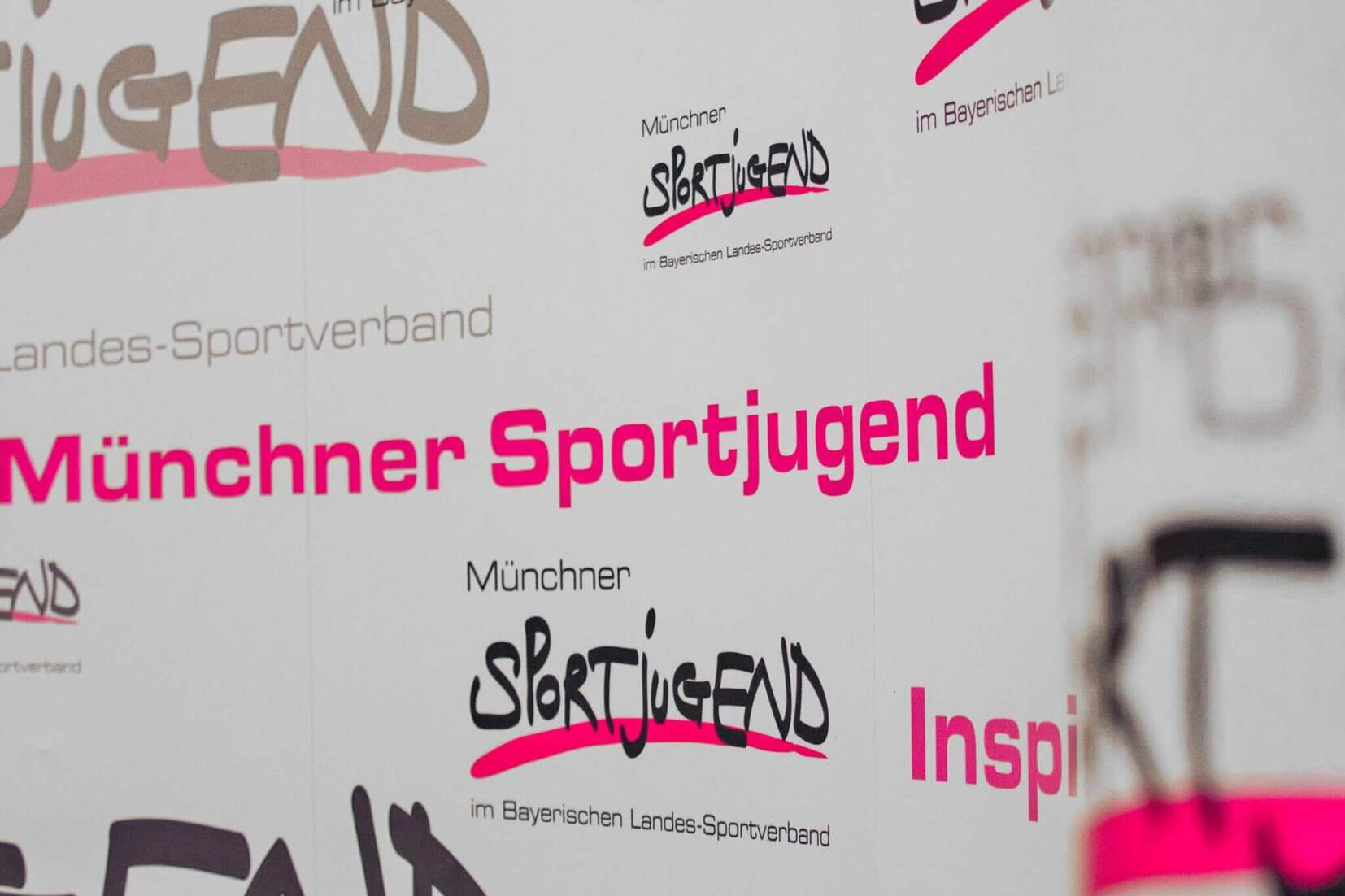 Hintergrund mit verschiedenen Logos und Schriftzügen der Münchner Sportjugend in unterschiedlichen Farben und Schriftarten.
