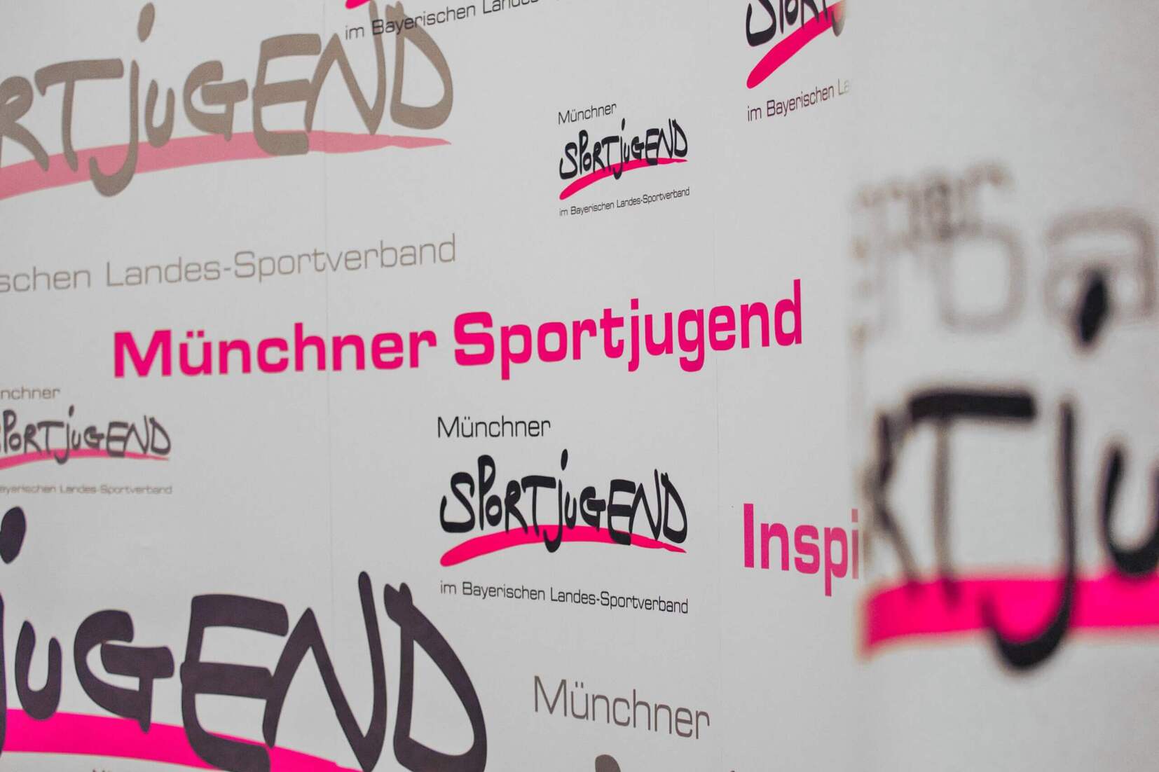 Hintergrund mit verschiedenen Logos und Schriftzügen der Münchner Sportjugend in unterschiedlichen Farben und Schriftarten.