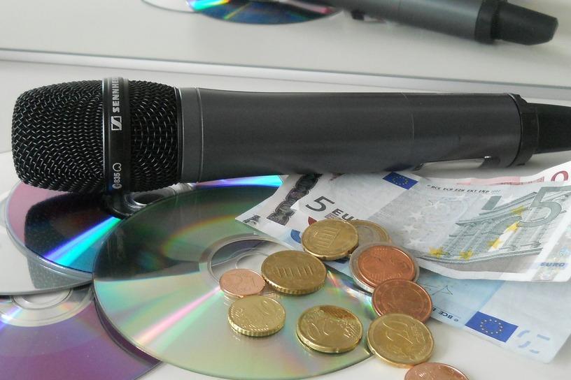 Mikrofon und CDs mit Münzen und Geldscheinen
